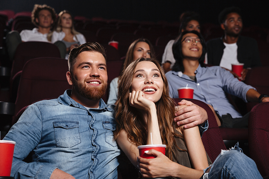 Happy young couple sitting at the cinema and enjoys watching the movie
